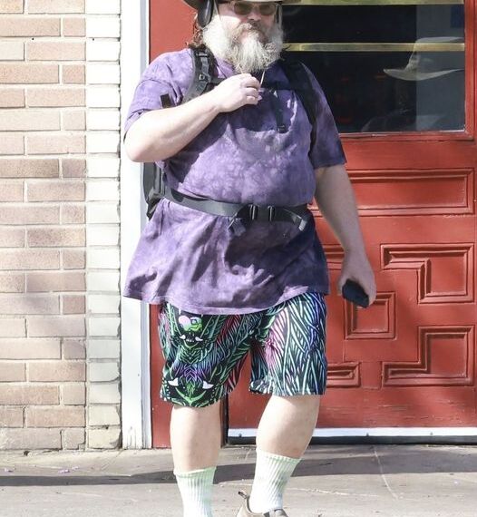 Los Feliz, CA  - *EXCLUSIVE*  - Jack Black is seen walking in Los Angeles, wearing a wide-brimmed hat, dark tie-dye T-shirt, brightly patterned shorts, white socks, and grey hiking shoes. He accessorizes with over-ear headphones, glasses, a black backpack, and holds a smartphone.

*UK Clients - Pictures Containing Children
Please Pixelate Face Prior To Publication*,Image: 882335759, License: Rights-managed, Restrictions: , Model Release: no, Pictured: Jack Black
